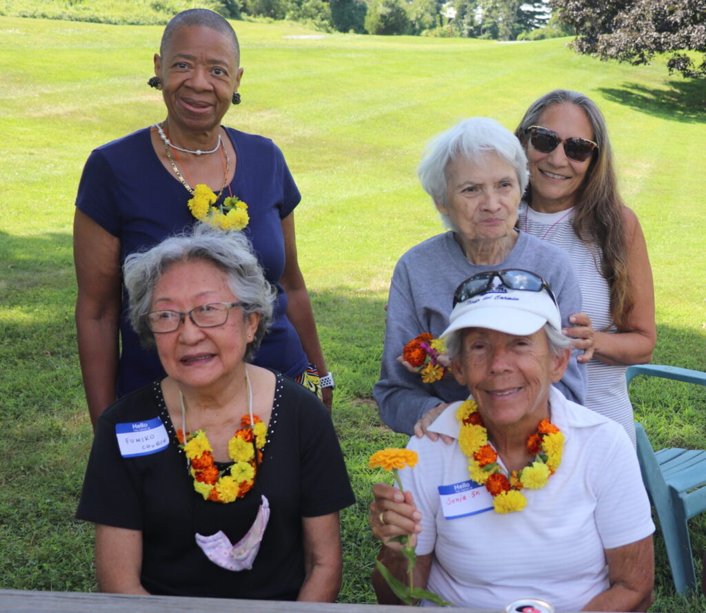 Small group of people wearing marigold necklaces smile at the camera